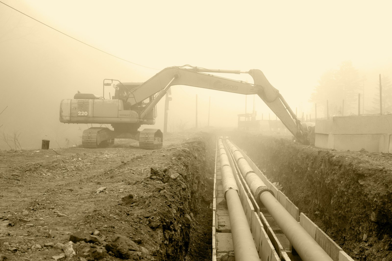 Excavator next to pipes laid in a trench